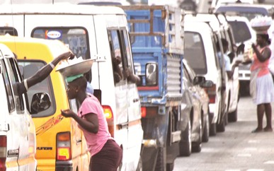 A teeneger vending sachet water in the middle of a road